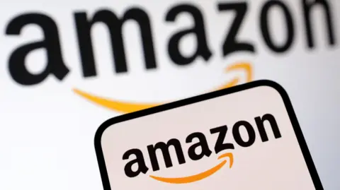 Amazon logo displayed on a smartphone screen, with a larger version of the company's logo on a white background behind it.